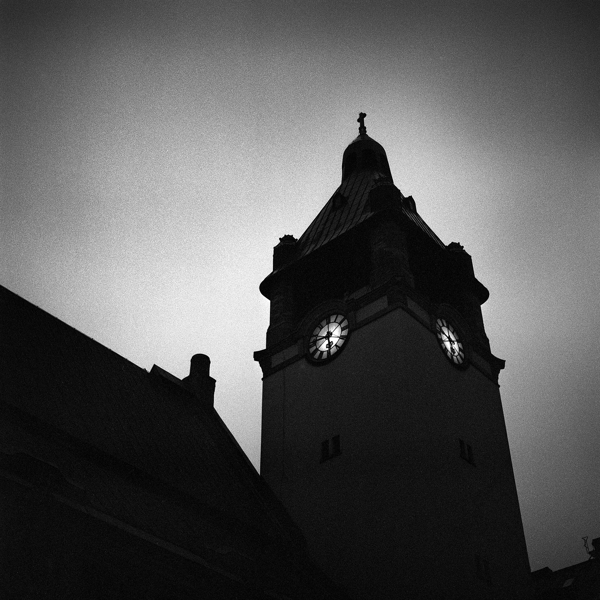 A clock tower silhouetted against a pale sky